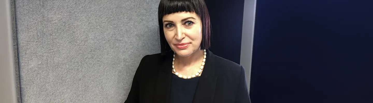 Woman smiling confidently in a professional setting, introduced as the company’s new Human Resources Officer.